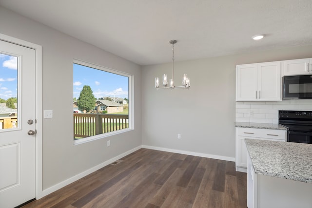 unfurnished dining area featuring an inviting chandelier, dark hardwood / wood-style floors, and a healthy amount of sunlight