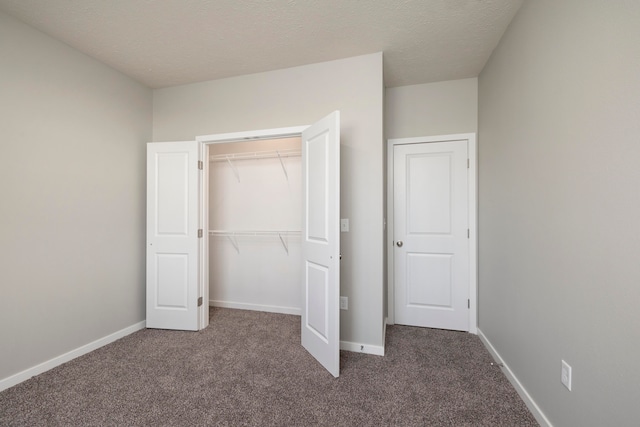 unfurnished bedroom with a closet, dark colored carpet, and a textured ceiling