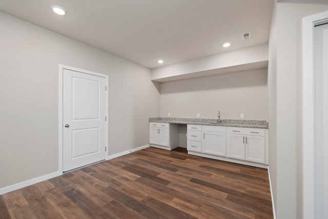 kitchen with dark wood-type flooring, sink, light stone counters, and white cabinetry