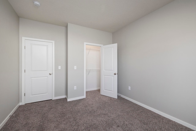 unfurnished bedroom featuring a closet and dark carpet