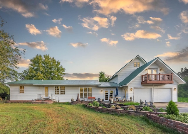 view of front of house featuring a balcony, a garage, and a lawn