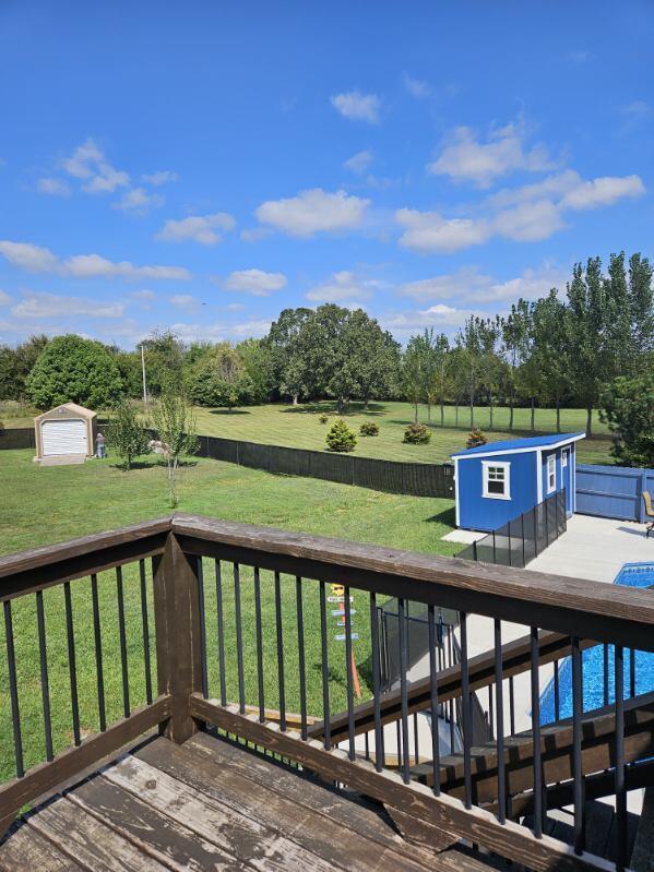 wooden deck featuring a rural view, a shed, and a lawn