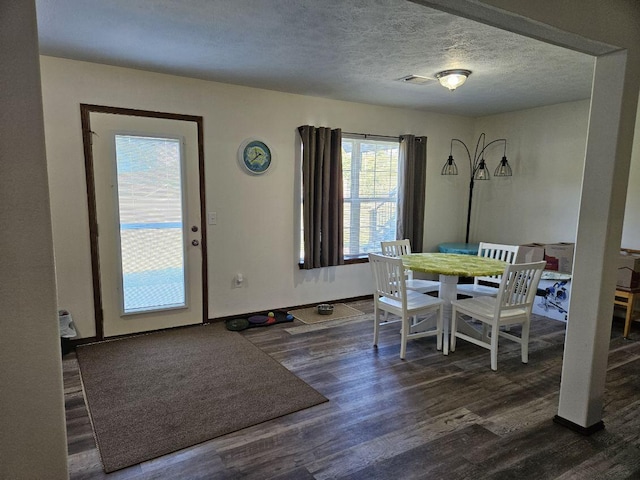 dining space with dark hardwood / wood-style floors and a textured ceiling