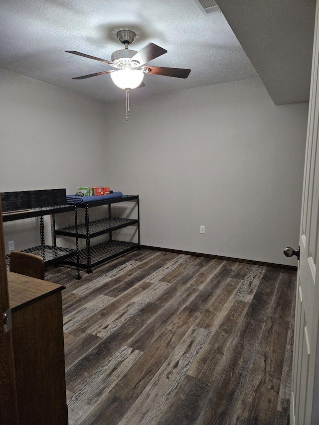 bedroom featuring dark wood-type flooring, a textured ceiling, and ceiling fan