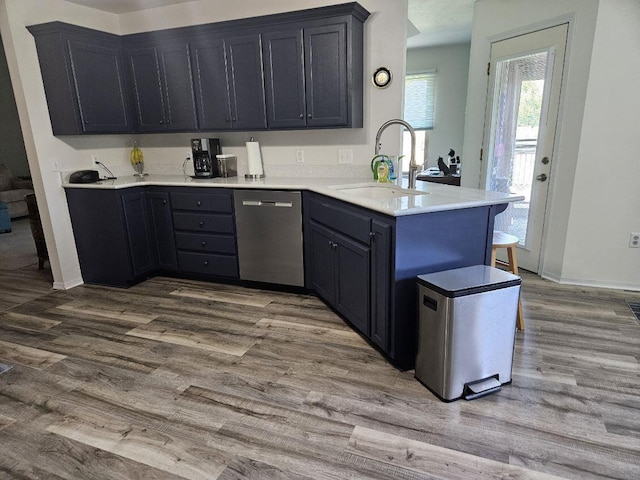 kitchen featuring dishwasher, kitchen peninsula, light hardwood / wood-style flooring, and sink