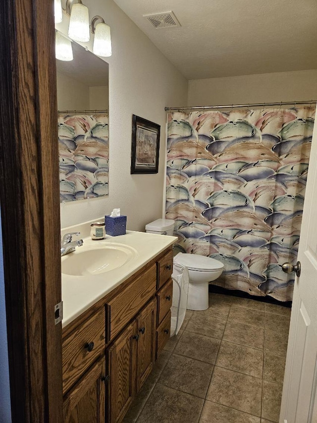 bathroom featuring vanity, tile patterned flooring, toilet, and a textured ceiling