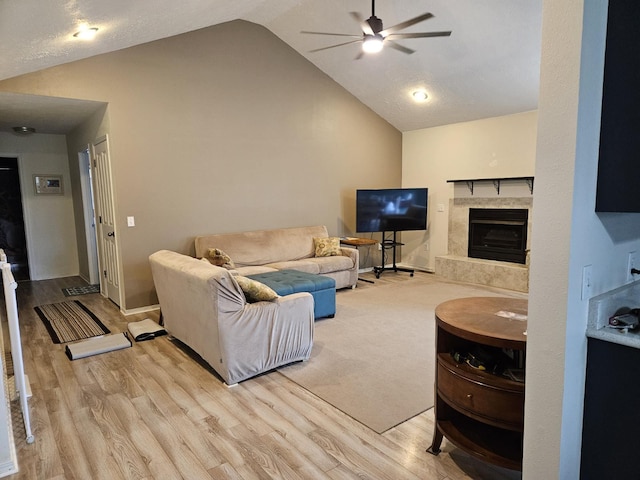 living room with ceiling fan, lofted ceiling, a premium fireplace, and light hardwood / wood-style floors