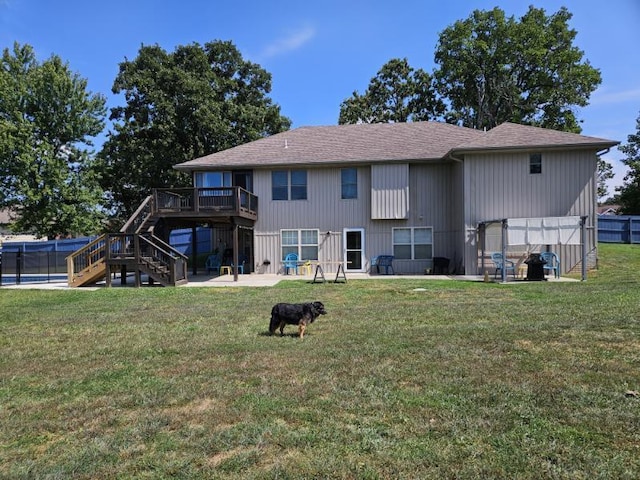 rear view of house featuring a wooden deck, a lawn, and a patio area