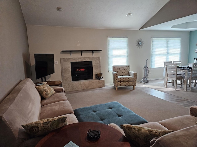 living room featuring lofted ceiling, plenty of natural light, light carpet, and a tile fireplace