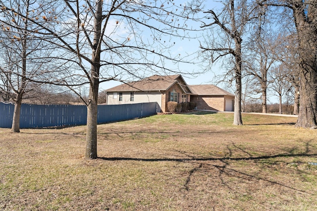 exterior space featuring a garage, a front yard, brick siding, and fence