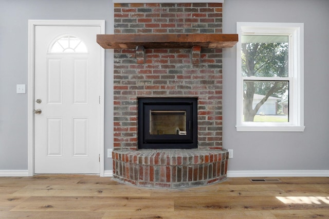 unfurnished living room featuring a brick fireplace and light hardwood / wood-style flooring