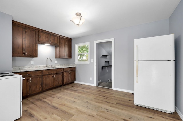 kitchen with light wood-type flooring, white appliances, dark brown cabinets, light stone counters, and sink