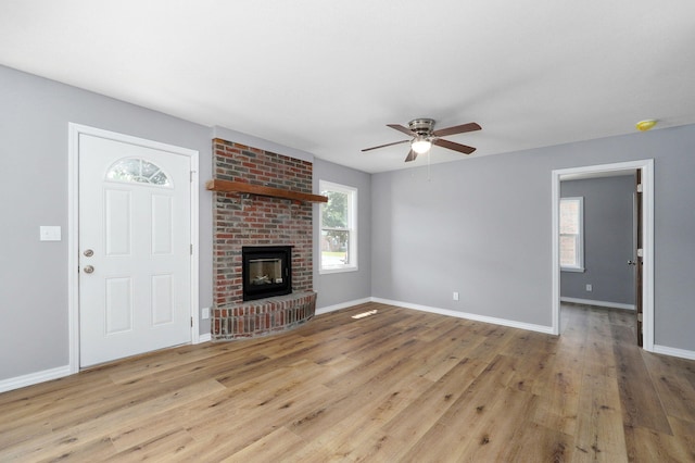 unfurnished living room with a brick fireplace, light hardwood / wood-style flooring, and ceiling fan