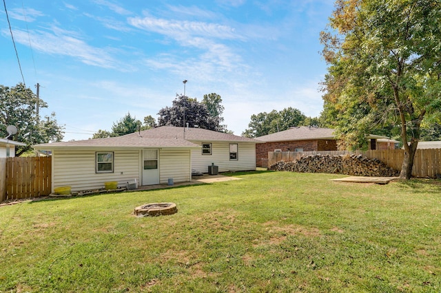 rear view of house featuring an outdoor fire pit and a yard