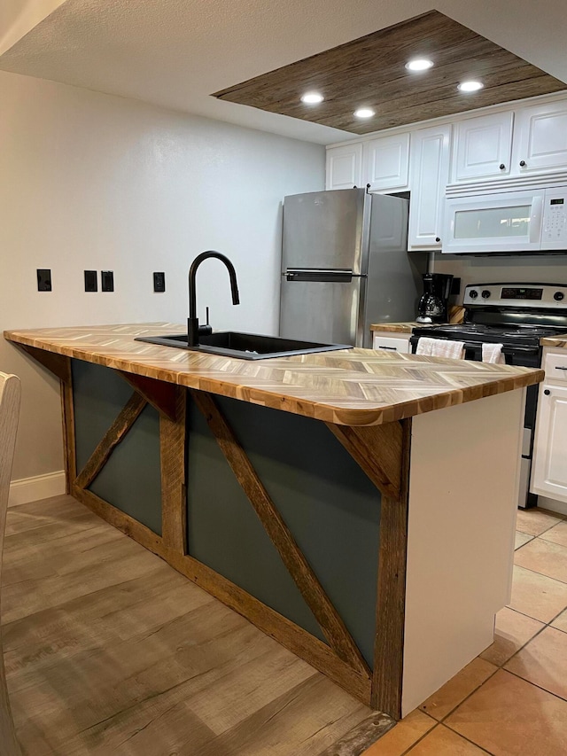 kitchen featuring white cabinets, stainless steel refrigerator, sink, light tile patterned floors, and electric range