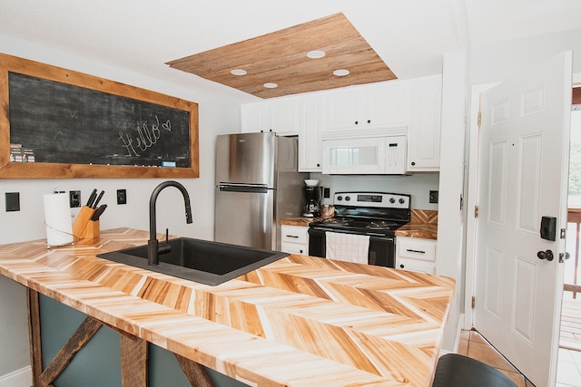 kitchen featuring light tile patterned flooring, stainless steel fridge, range with electric stovetop, sink, and white cabinetry