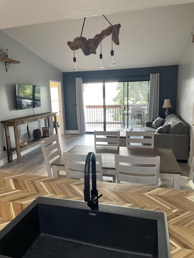 living room featuring a textured ceiling, lofted ceiling, light wood-type flooring, and sink