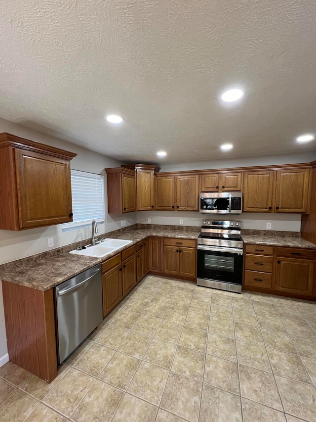 kitchen with light tile patterned floors, a textured ceiling, stainless steel appliances, and sink