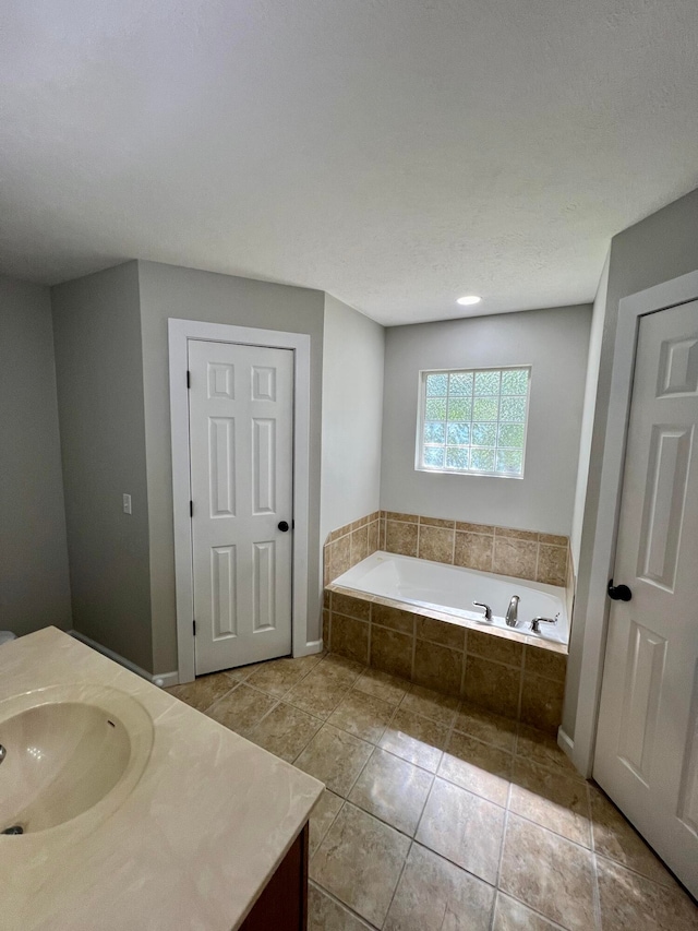 bathroom with tile patterned flooring, vanity, and tiled bath