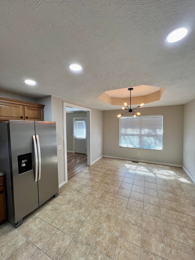 kitchen featuring a textured ceiling, stainless steel fridge, a chandelier, and plenty of natural light