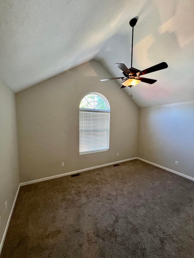 unfurnished room with ceiling fan, dark carpet, vaulted ceiling, and a textured ceiling