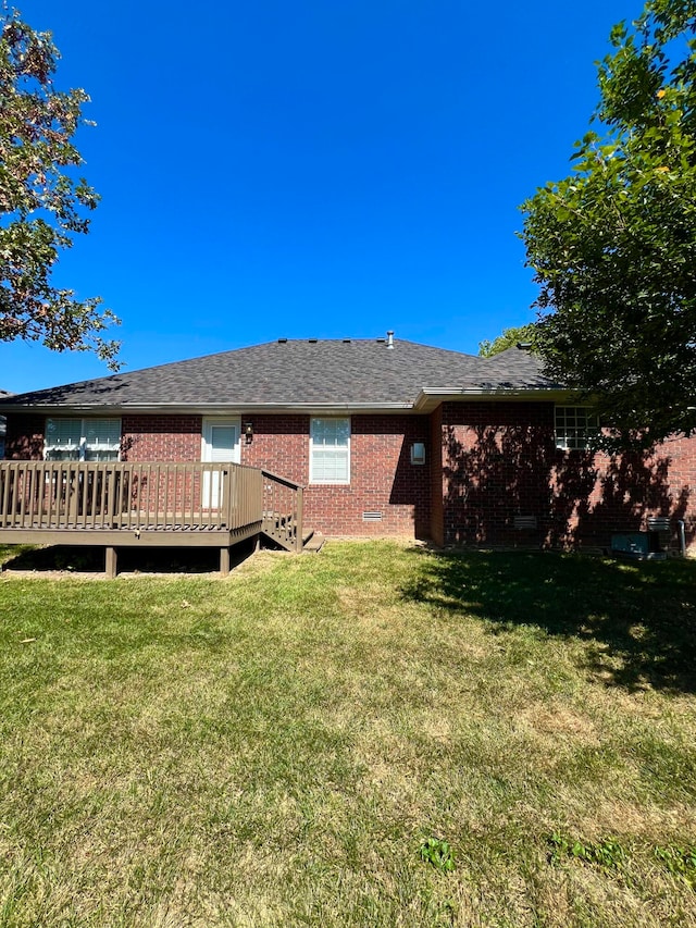 rear view of property featuring a wooden deck and a lawn