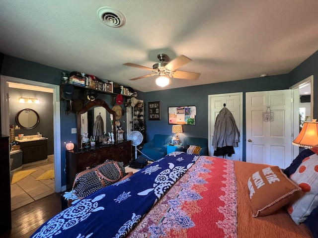 bedroom with wood-type flooring, ensuite bath, and ceiling fan