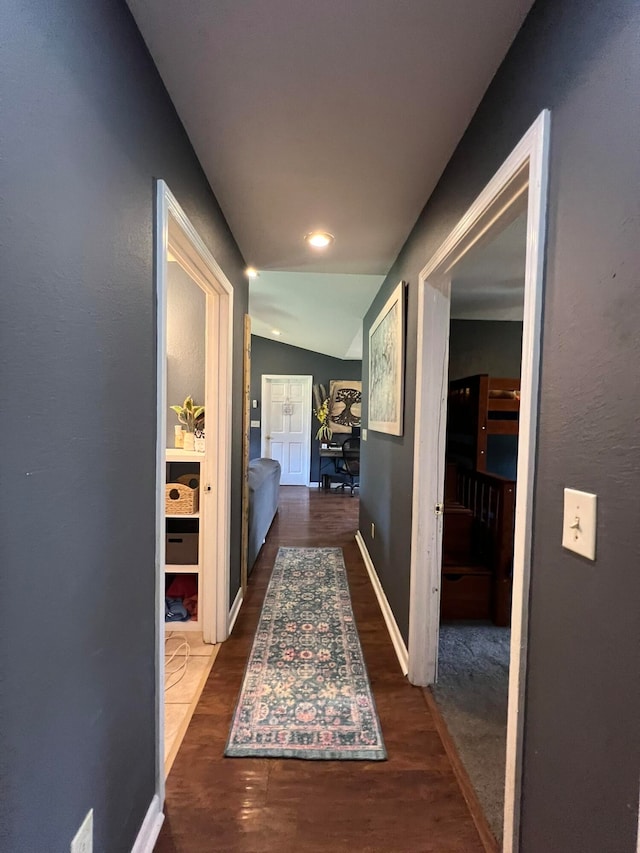 hall with lofted ceiling and dark hardwood / wood-style flooring