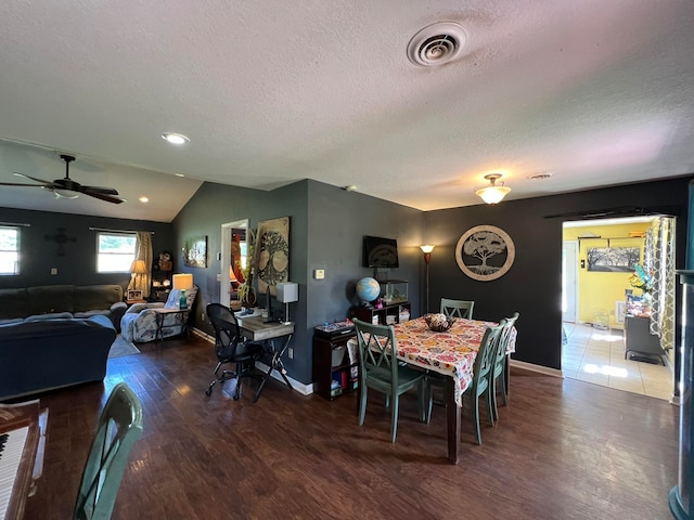 dining area featuring ceiling fan, vaulted ceiling, dark hardwood / wood-style floors, and a textured ceiling