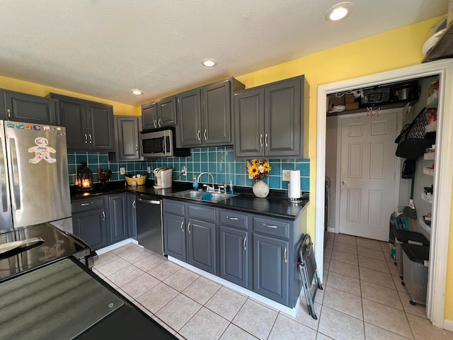 kitchen featuring light tile patterned flooring, gray cabinets, tasteful backsplash, sink, and stainless steel appliances