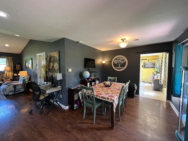 dining space with hardwood / wood-style flooring, lofted ceiling, and a textured ceiling