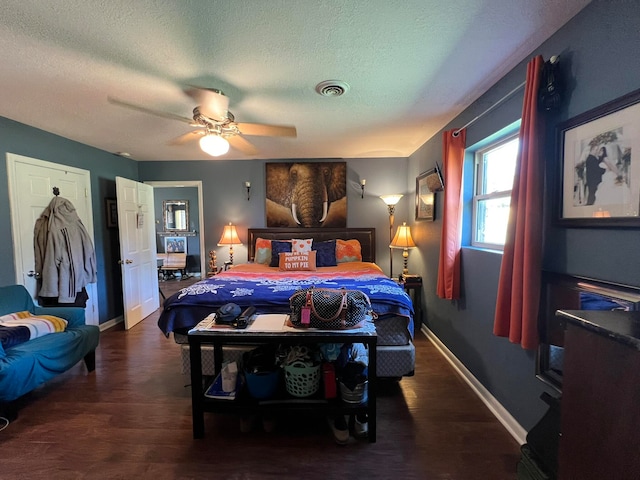 bedroom with a textured ceiling, ceiling fan, and dark hardwood / wood-style flooring