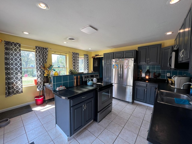 kitchen with a center island, stainless steel appliances, sink, light tile patterned floors, and backsplash