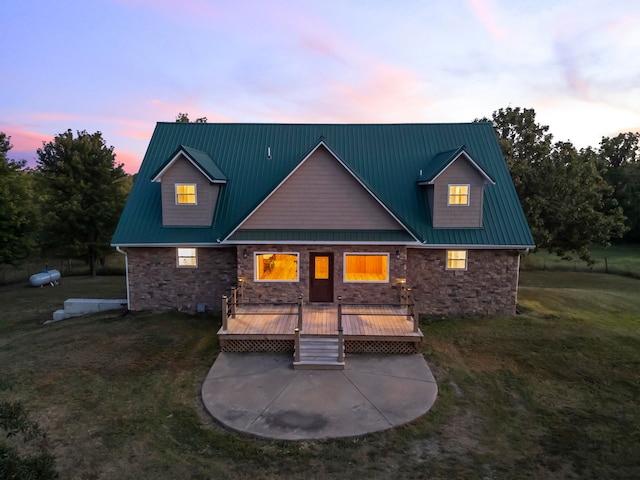 back house at dusk with a deck and a lawn