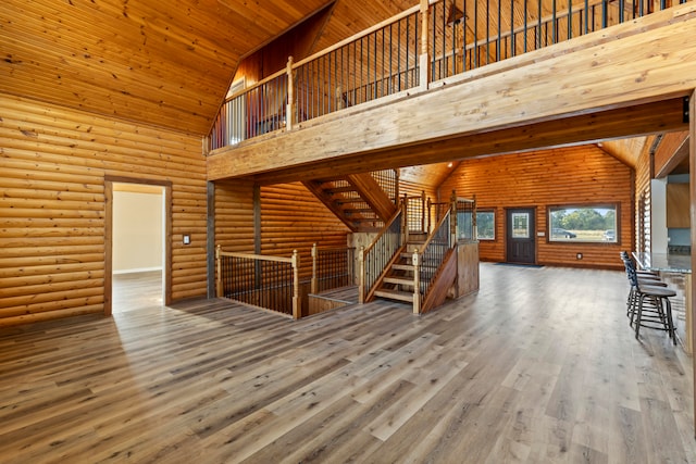 unfurnished living room featuring wood-type flooring, wood ceiling, high vaulted ceiling, and log walls