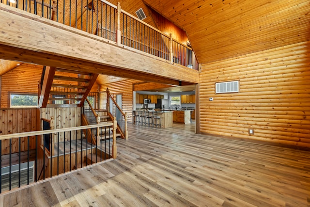 interior space with wood-type flooring, wood ceiling, rustic walls, and high vaulted ceiling