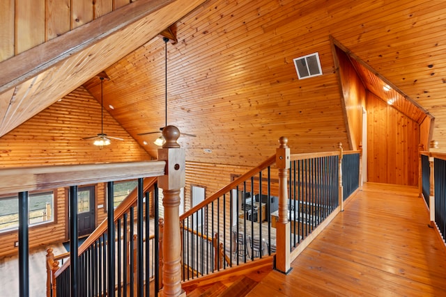 corridor featuring light hardwood / wood-style flooring, wood walls, wood ceiling, and high vaulted ceiling