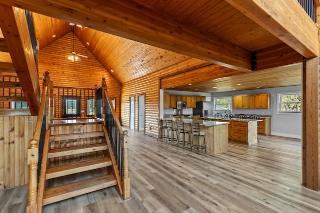 staircase with ceiling fan, wood ceiling, beam ceiling, wood-type flooring, and high vaulted ceiling