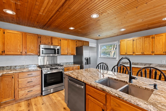 kitchen with stainless steel appliances, light hardwood / wood-style floors, sink, and light stone counters