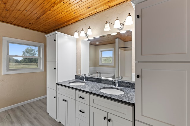 bathroom with a bath, a healthy amount of sunlight, vanity, and wood-type flooring