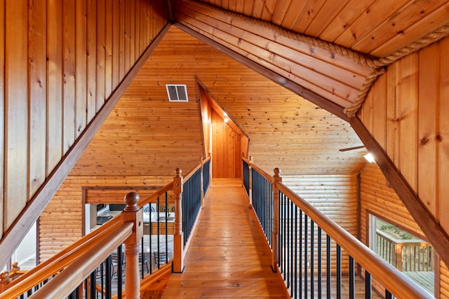 hallway with wooden walls, wood ceiling, hardwood / wood-style floors, and vaulted ceiling