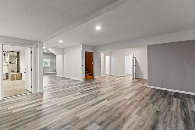 unfurnished living room with beam ceiling and light hardwood / wood-style floors