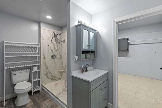 bathroom featuring vanity, toilet, hardwood / wood-style flooring, and tiled shower