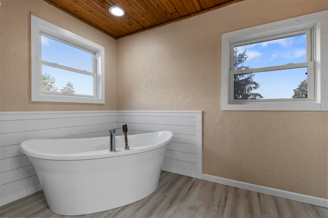 bathroom with a bath, wood ceiling, and hardwood / wood-style floors