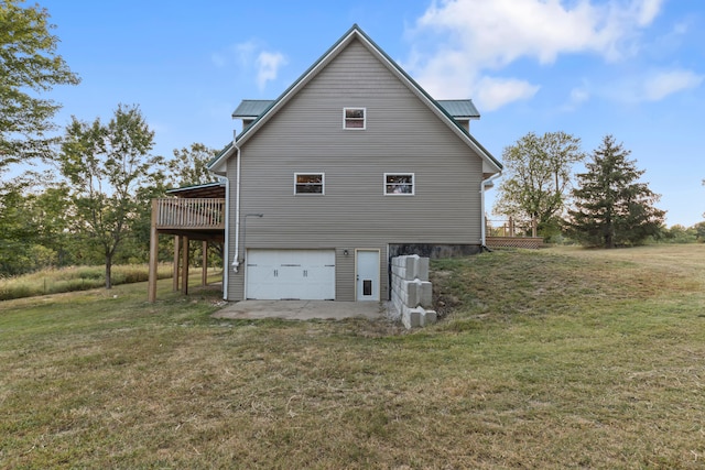 back of property with a garage, a yard, and a wooden deck