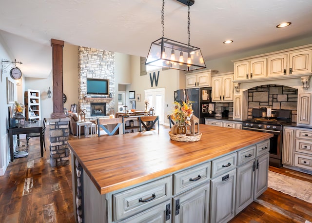 kitchen featuring black fridge, gas range, decorative light fixtures, dark hardwood / wood-style flooring, and butcher block counters