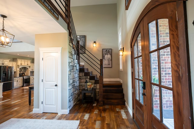 entryway with french doors, dark hardwood / wood-style floors, high vaulted ceiling, and an inviting chandelier