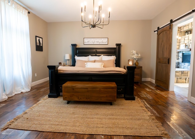 bedroom featuring a barn door, ensuite bath, an inviting chandelier, and dark hardwood / wood-style floors