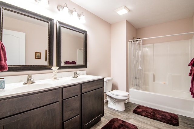 full bathroom with hardwood / wood-style floors, vanity, shower / tub combo, and toilet