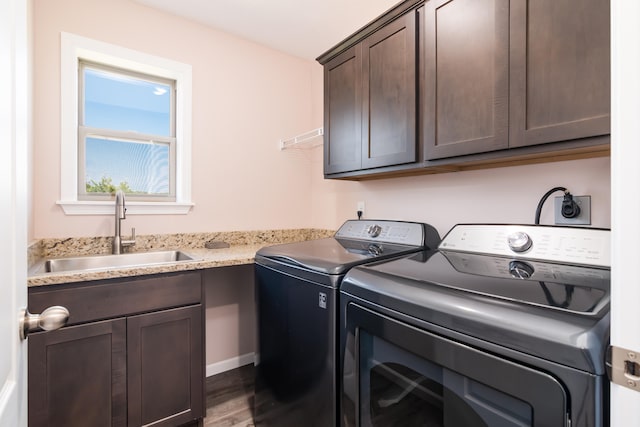 laundry room featuring dark wood-type flooring, cabinets, sink, and washer and clothes dryer